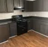 Sleek modern kitchen featuring dark cabinetry, polished countertops, and elegant wood flooring.