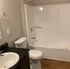 Modern bathroom with sleek black countertop, pristine white fixtures, and warm wood flooring.