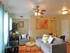 Inviting living room with cozy gray sofas, vibrant artwork, and a stylish dining area in a serene apartment setting.