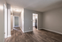 Inviting apartment hallway with sleek hardwood flooring leading to a spacious kitchen with modern white cabinetry.