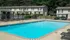 Inviting apartment complex featuring a pristine swimming pool with sun loungers, set against charming duplex townhouses.