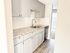 Bright modern kitchen with sleek granite countertops, elegant gray cabinetry, and a built-in dishwasher, offering a welcoming entry to the living area with natural light.