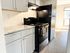 Contemporary kitchen with sleek black appliances, elegant granite countertops, and stylish grey cabinets, perfect for modern living.