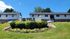 Inviting apartment complex with charming landscaped gardens, vibrant flowers, and a welcoming sign under a clear blue sky.