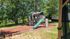 Charming outdoor play area with a modern play structure set amid lush greenery, perfect for family fun and relaxation.