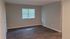 Spacious empty room with elegant wooden flooring and a window allowing natural light.