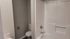 Modern bathroom featuring sleek white bathtub, elegant fixtures, and a neatly designed toilet area with fresh decor.