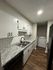 Modern kitchen with sleek granite countertops, white cabinetry, and convenient in-unit laundry appliances.