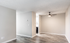 Modern apartment interior showcasing a bright living area with elegant wood flooring and stylish ceiling fan, seamlessly leading into a cozy kitchen.