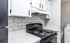 Modern kitchen with sleek white cabinets, pristine countertops, and a stylish black stove next to a convenient laundry area.