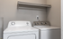 Modern apartment laundry room equipped with a high-efficiency washer and dryer beneath a handy storage shelf. Bright and functional space for convenient living.