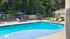 Inviting outdoor pool area with lounge chairs and blue umbrellas, surrounded by lush greenery for a relaxing retreat.