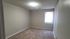 Cozy, well-lit bedroom with soft carpeting and a bright window, ideal for restful nights.