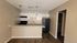 Modern kitchen with sleek countertops, stylish pendant lighting, and dark appliances, perfect for culinary adventures.