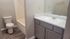 Modern bathroom with elegant wooden flooring, a sleek vanity, and bright lighting. Features a bathtub and a toilet for a serene and practical space.