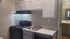 Modern kitchen with sleek cabinetry, electric stove, single stainless steel sink, and a view into the adjacent bathroom.