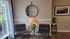 Cozy corner featuring elegant leather chairs, a stylish round mirror, and a welcoming side table with greenery and a warm lamp.