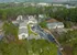 Scenic aerial view of a tranquil apartment complex nestled amidst lush greenery with ample parking and well-maintained roads.