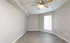 Modern empty room with sleek hardwood flooring, neutral walls, and a ceiling fan, perfect for personalization.