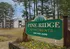 Charming Pine Ridge Apartments nestled among lush trees, featuring inviting signage and a picturesque setting.