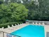 Inviting outdoor pool area with lush greenery, ample lounge chairs, and a serene atmosphere for relaxation and enjoyment.