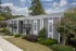 Charming apartment building with modern gray facade, surrounded by lush greenery and trees, offering serene living.