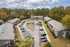 Scenic aerial view of a tranquil apartment complex with lush greenery, ample parking, and charming multi-story buildings.