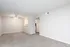 Bright spacious living area with elegant ceiling fan and cozy carpet flooring, leading to a sleek kitchen.