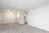 Spacious and bright living area with plush carpeting, a ceiling fan, and neutral tones, leading into a cozy kitchen space.