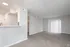 Bright and spacious apartment living room with plush carpeting, open kitchen area, and sliding glass doors to let in natural light.