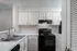 Contemporary kitchen with sleek white cabinets, modern black appliances, and spacious countertops for effortless cooking.