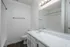 Modern bathroom with sleek white cabinets, expansive mirror, and elegant lighting under a soft ambiance, offering a clean and refreshing feel.