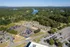 Aerial view of a tranquil lakeside apartment complex surrounded by lush greenery and ample parking.
