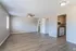 Spacious living area with elegant wood flooring, ceiling fan, and an adjacent cozy kitchen featuring modern cabinetry.