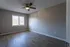 Spacious bedroom with modern ceiling fan, elegant wood flooring, and ample natural light from large window.