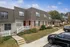 Charming townhouse exterior with brick and siding facade, red doors, and inviting front porches, surrounded by lush landscaping and convenient parking.