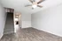 Modern apartment interior with elegant wood flooring, cozy carpeted staircase leading to the upper level, and a stylish ceiling fan illuminating the living space.