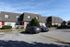 Charming townhouse community with modern architecture, featuring well-maintained landscaping and spacious parking area under a clear blue sky.