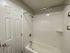 Elegant bathroom featuring a pristine white bathtub, modern tiled walls, and a sleek shower setup.