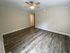 Spacious room with elegant wood flooring and a modern ceiling fan, perfect for cozy living.