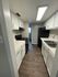 Modern galley kitchen with sleek white cabinets, elegant dark appliances, and rich wood flooring, creating a stylish and efficient cooking space.