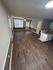 Inviting apartment living space with elegant hardwood flooring and large, sunlit windows.
