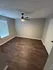 Inviting room with elegant wooden floors, modern ceiling fan, and abundant natural light from a large window.