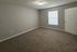 Spacious carpeted bedroom with soft neutral tones and ample natural light from a large window.