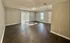 Bright and airy living room with elegant dark wood flooring, large window, and sliding glass doors leading to outdoor space.