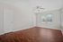 Bright and airy room with elegant hardwood floors, large window, and modern ceiling fan, perfect for comfortable living.