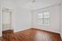 Bright, empty room with sleek hardwood flooring and a large window allowing natural light. Perfect blank canvas for personalization.
