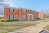 Inviting two-story brick apartment complex with modern windows, surrounded by lush greenery and well-maintained pathways.