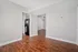 Bright apartment interior with polished hardwood floors, open layout, and modern kitchen with stainless steel fridge.