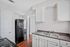 Charming kitchen featuring sleek black appliances, elegant white cabinetry, and rich hardwood flooring.